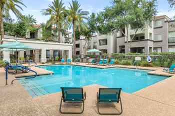 Resort style pool with lounge chairs and umbrellas